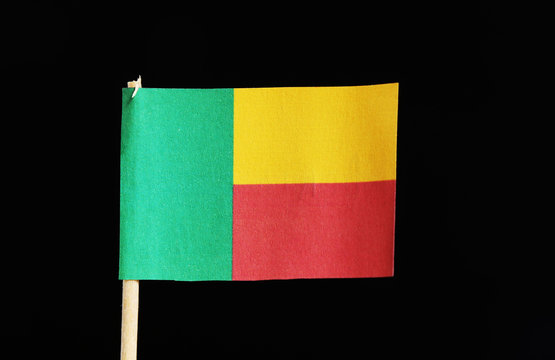 A original and official flag of Benin on toothpick on black background. A horizontal bicolor of yellow and red with a green vertical band at the hoist.