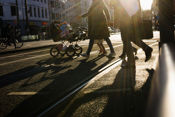 Anonymous people crossing street in sunset