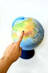 the finger of the hand points to the spinning ball of the globe