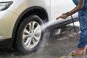 Worker spraying water onto car to wash