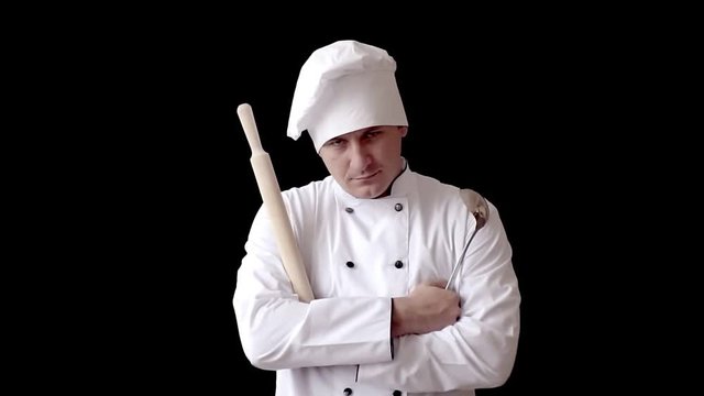 disgruntled angry chef with rolling pin in white kitchen suit on black wall background. concept idea of cooking