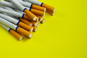 Heap of cigarettes with tobacco and filter scattered on yellow background with copy space for your text or logo. Stop smoking concept