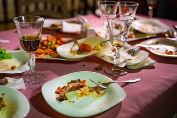 The leftover food and dirty dishes on the restaurant table. Scraps left over after the party.