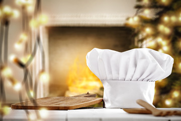 Fototapeta na wymiar White cook hat on white wooden table and christmas decoration. Free space for your products. 
