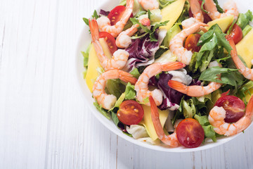 Mix of salad with shrimps , avocado and cherry tomatoes . Healthy food background