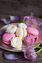 White and pink macaroons, zefir or zephyr and flowers on vintage plate on wooden background