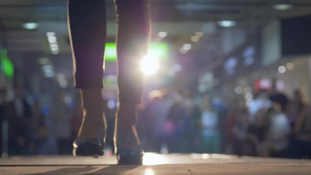 elegant female models in costumes walk the catwalk during a fashion show in lighting on background blurred audience