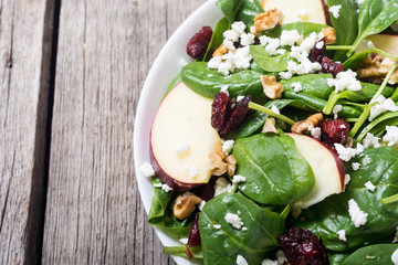 Autumn spinach salad with apple , cheese , walnut and dried cranberry . Healthy vegetarian food