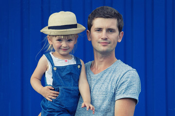 Father and daughter cuddle and laugh on a blue background. Copy space.
