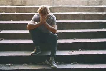 Stressed young man sitting on stairs outdoors