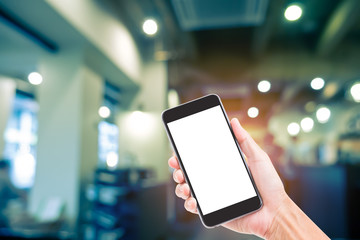 Man hand holding mobile phone with blurred image of coffee shop background