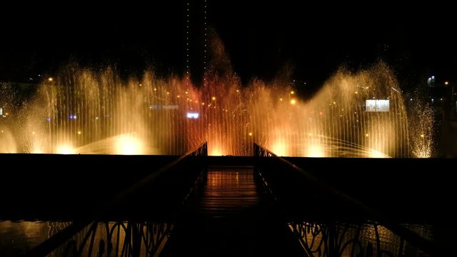 Amazing dancing fountains and bursts of water at night in the resort city - colors reflected on the bridge and music of the night show