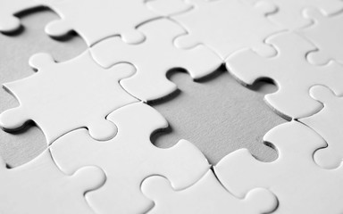 Incomplete jigsaw puzzle on light background, closeup