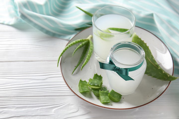 Glass and jar with fresh aloe vera juice on wooden table