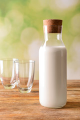 Bottle of fresh milk and empty glasses on wooden table