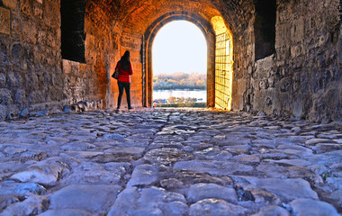 A tourist walk under one of old gates in Kalemegdan fortress and castle with Sava river and landscape in background. Belgrade Serbia © poludziber