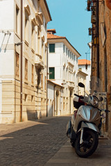 Obraz na płótnie Canvas Treviso, Italy August 7, 2018: a moped is parked on a city street.