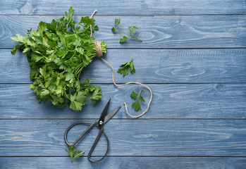 Fresh aromatic parsley with scissors on color wooden background © Pixel-Shot