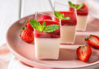 Glasses with tasty strawberry panna cotta on plate, closeup