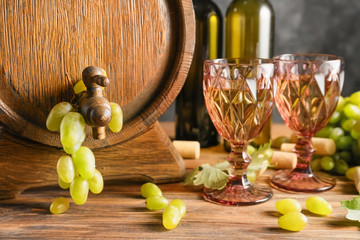 Barrel and glasses with wine and ripe grapes on wooden table