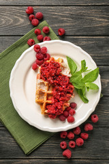 Tasty waffle with fresh raspberry on plate