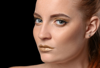 Beautiful woman with golden make up against dark background