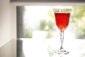 Glass of tasty wine on table near window