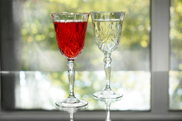 Glasses of tasty wine on table near window