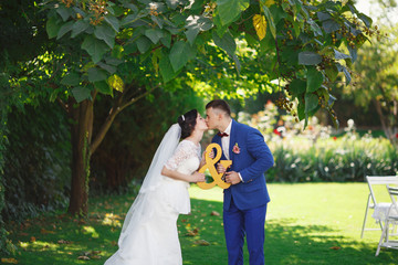 Just married loving hipster couple in wedding dress and suit in the park. Happy bride and groom walking in the beautiful garden. Romantic Married young family.