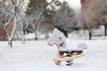 Playground equipment rocking horse covered in snow