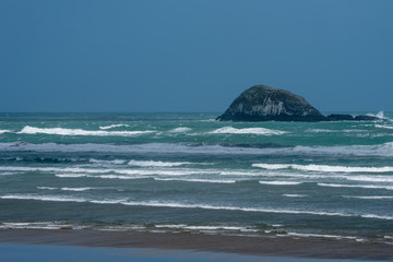 Island off the coast at Muriwai Beach on a windy day