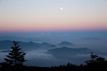 The moon shines over a sea of clouds, during sunrise at Emei-Shan, Sichuan province, China