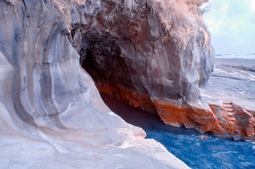 A hole in the rock in a cliff near a beach