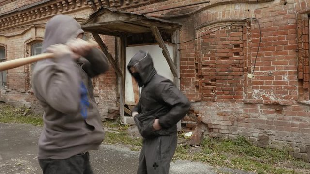 Two hooligans attacking each other with bat and fists on street