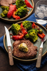 Grilled Beef steak with garlic butter and vegetables. Meat with grilled bell pepper, broccoli and onions.