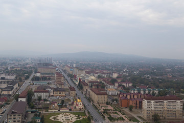 Obraz premium Grozny, Russia: 10.07.2015. Daily life in Chechen Republic. Aerieal view of the Akhmat Kadyrov Avenue, Orthodox Church of St. Michael the Archangel, multistorey buildings and mountains