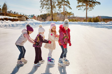 Fototapeta na wymiar Four little happy girls are skating. They have fun with friends.