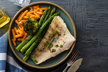 Pike perch fillet with asparagus, broccoli and carrots. Fried fish with stewed greens