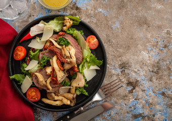Salad with warm beef with oyster mushrooms, tomatoes and greens. Top view