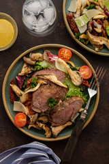 Salad with warm beef with oyster mushrooms, tomatoes and greens. Top view