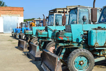 Fototapeta na wymiar Russia, Temryuk - 15 July 2015: Tractor. Bulldozer and grader. Tractor with a bucket for digging soil. The picture was taken at a parking lot of tractors in a rural garage on the outskirts of Temryuk.