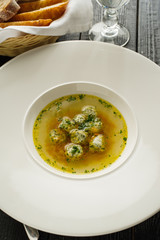Soup broth with meatballs in a white plate. Concept for a menu in a restaurant