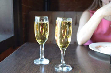 two glasses of champagne on a table in a restaurant. wine or champagne pouring in wine glass. concept for drink and beverage.Blur background