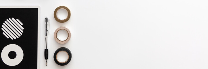 Panoramic photo of white desk copy space seen from above with a pen, a notebook with wheels and...