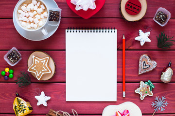 Open notebook with blank pages, gifts, cup of chocolate with marshmallow and sweets. Flat lay, top view. Christmas planning and New Year concept, holiday decorations 2019 Goals. 