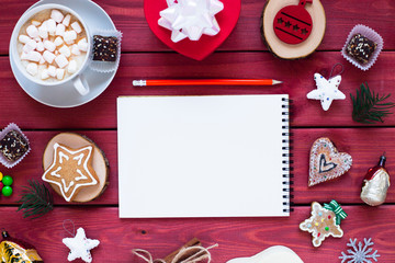 Open notebook with blank pages, gifts, cup of chocolate with marshmallow and sweets. Flat lay, top view. Christmas planning and New Year concept, holiday decorations 2019 Goals. 