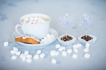 Hot coffee with marshmallows and gingerbread cookies on the light gray background. Beautiful Christmas decorations with gifts and sweets. Space for a text. Close up.