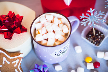 Hot coffee with marshmallows and gingerbread cookies on the light gray background. Beautiful Christmas decorations with gifts and sweets. Space for a text. Close up.