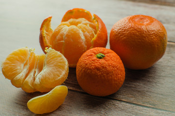 tangerines, peeled tangerine and tangerine slices on a white wooden table