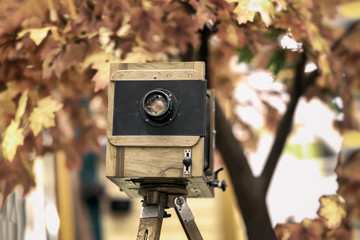 Vintage wooden view photocamera and tripod. Cocept retro, nostalgia and time. Autumn background